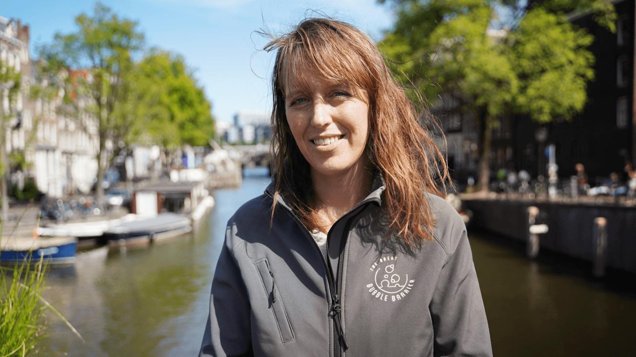 Team member of the Great Bubble Barrier in front of an Amsterdam canal
