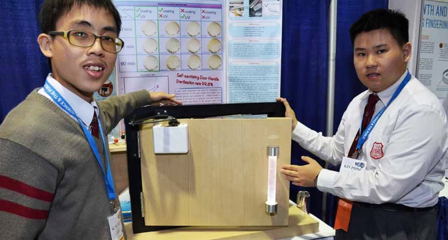 Sum Ming (“Simon”) Wong, 17 (left), and Kin Pong (“Michael”) Li, 18, of Hong Kong show off the self-sanitising door handle they developed. It’s powered by opening and closing the door.