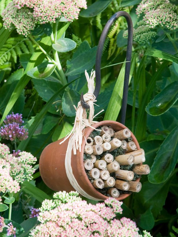 A terracotta pot, some bamboo canes, and raffia are all you need to make this little hanging bee hotel.