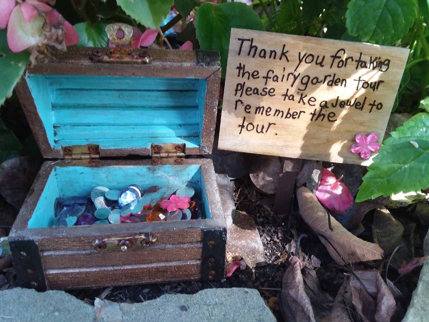 “Well, I hope you enjoyed your fairy garden tour”, say the words on the sign, “because I really enjoyed it so much. Please take a jewel to remember your visit.”