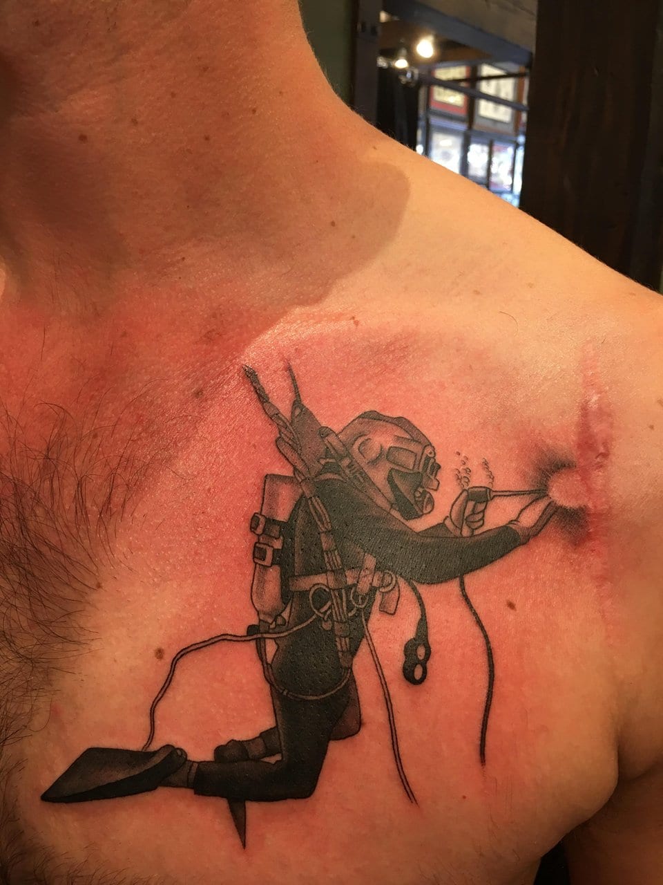 Here is a tattoo of an underwater welder closing up a tear in this person’s shoulder. It looks like he has had some kind of shoulder surgery, but is currently under repair.