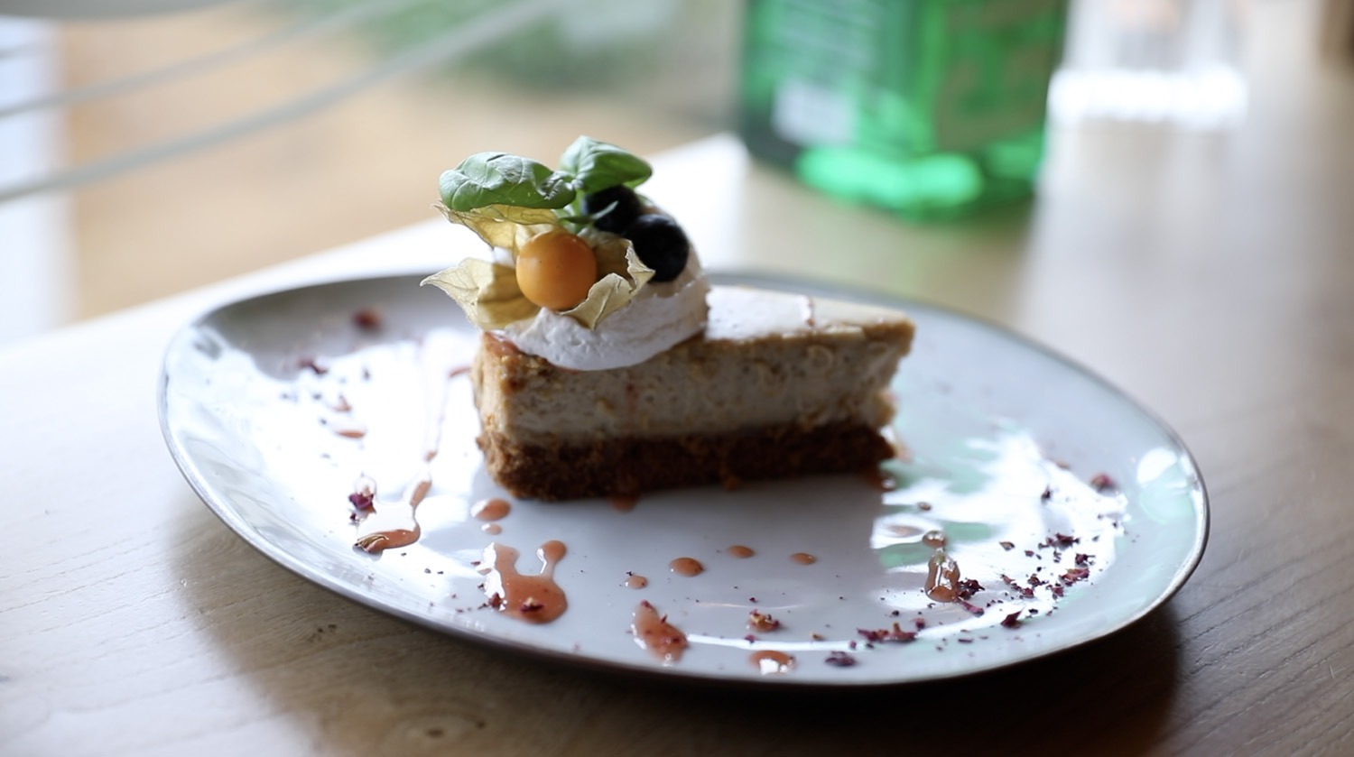 Deze cheesecake op basis van noten is subliem opgemaakt met vegan crème, basilicum en bessen.