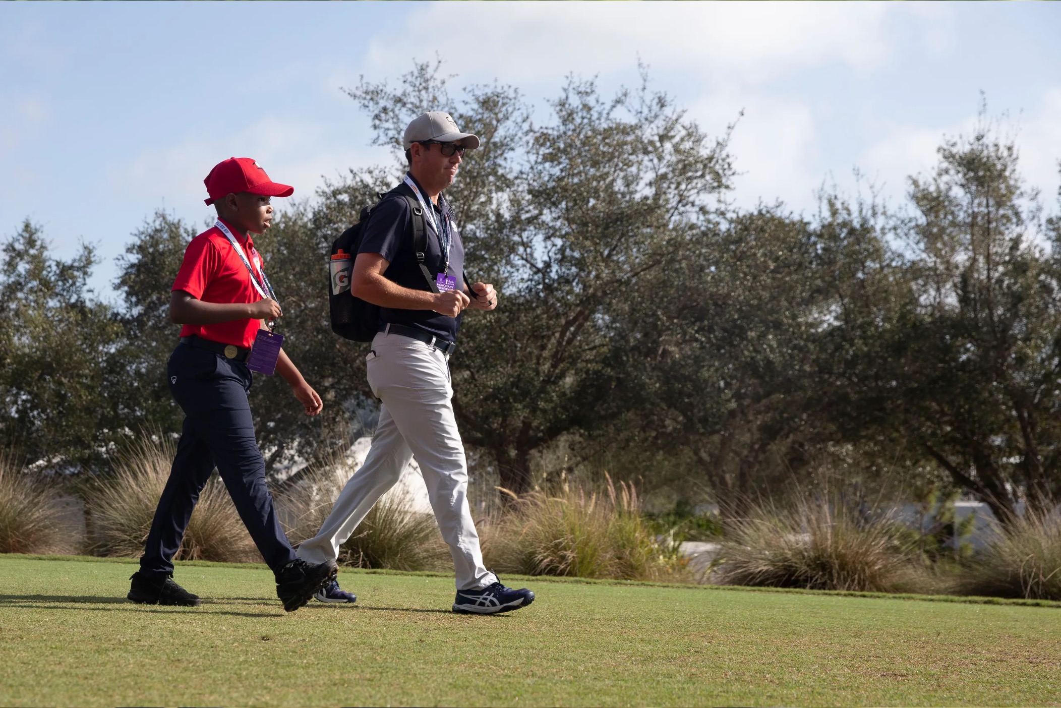 Carter Bonas, de 10 años, y su instructor de golf Corey Henry, del Country Club de Coral Springs, salen de la caja de salida en el primer hoyo durante la primera ronda del Chubb Classic, el viernes 18 de febrero de 2022, en el Tiburón Golf Club en The Ritz-Carlton Golf Resort en Naples, Florida.