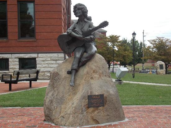 The Dolly Parton Statue is a popular stop for country music fans located in the center of the Sevier County Courthouse lawn in the heart of Sevierville, Dolly’s hometown. This bronze statue by sculptor Jim Gray portrays Parton as a young woman, perched on a rock while casually strumming her guitar. The statue debuted in 1987.