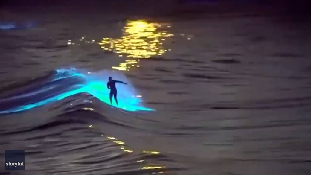 His video shows the surfer paddling across the water on a surfboard ringed in light, before catching a glowing wave and riding it with the sunset in the background.
