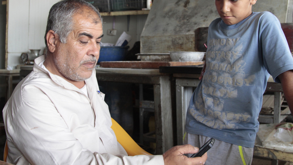Mohanad Al-Khariat bekijkt foto's en messages op zijn iPhone die hij van zijn broer uit Chicago heeft gekregen.