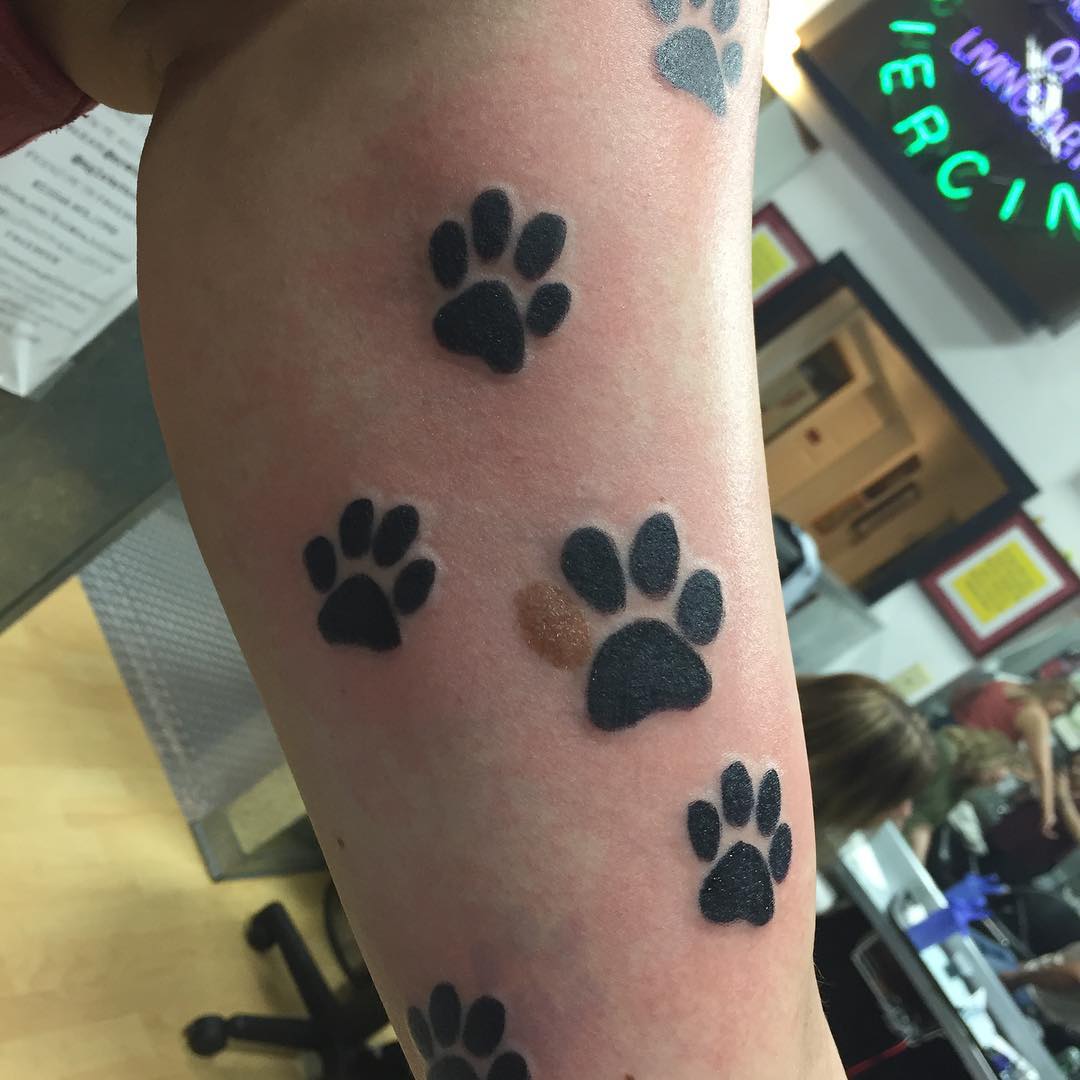 Esta persona, a quien obviamente le gustan los perros, incorporó un lunar en el diseño de su tatuaje. Me sorprende que se haya hecho tantos tatuajes de huellas, ni más ni menos que en el brazo. Le deben gustar mucho los perros.
