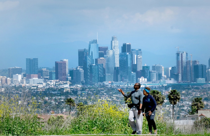 A couple takes a stroll at Kenneth Hahn Park in the Baldwin Hills Mountains of Los Angeles, with clean skies between them and downtown Los Angeles on Tuesday, March 24, 2020.